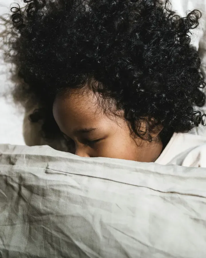 A teen asleep, face half buried in a white pillow